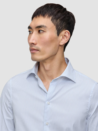 A man wearing an Elevated Shirt Regular Classic Blue Striped, an elegant, light blue and white pinstriped Pima cotton button-down shirt.