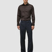A man wearing an Elevated Shirt Regular Dark Brown tucked into dark trousers and brown loafers, reflecting a clean Scandinavian design aesthetic.