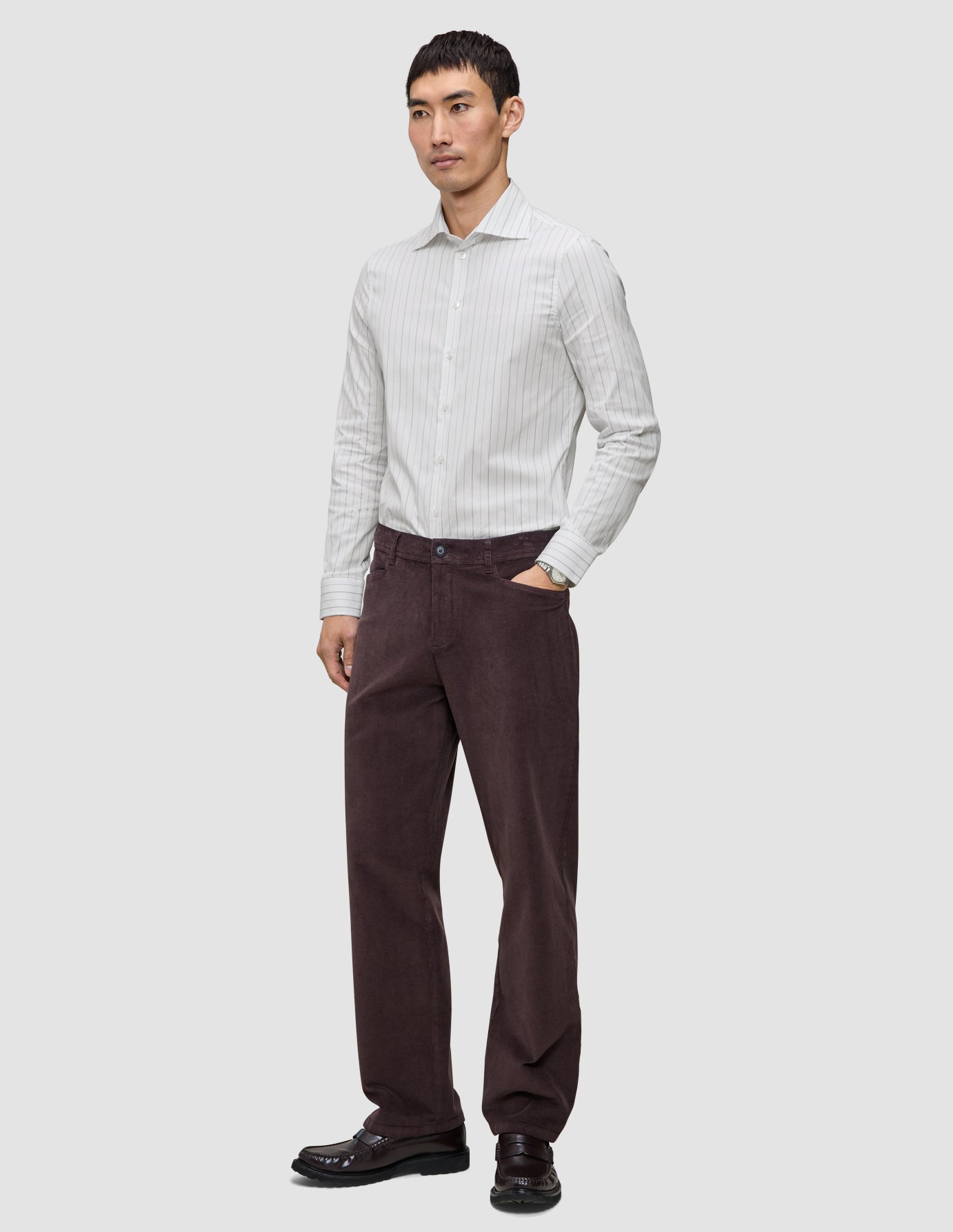 A man wearing an Elevated Shirt Regular Light Grey Striped long-sleeve dress shirt, dark brown trousers, and dark loafers.