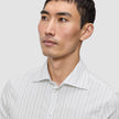 A man wearing an Elevated Shirt Regular Light Grey Striped, a white dress shirt featuring thin, light grey vertical stripes.