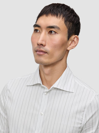 A man wearing an Elevated Shirt Regular Light Grey Striped, a white dress shirt featuring thin, light grey vertical stripes.