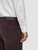 A person wearing an Elevated Shirt Regular Light Grey Striped in thin grey vertical stripes and dark brown corduroy trousers.