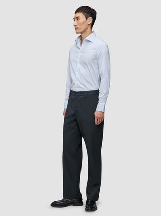 A man wearing an Elevated Shirt Slim Classic Blue Striped light blue striped slim fit shirt, dark trousers, and black dress shoes.
