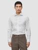 A man wearing a slim fit, long-sleeved Elevated Shirt White Slim tucked into brown trousers.