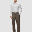 A man wearing an Elevated Shirt White Slim tucked into brown trousers and dark loafers.