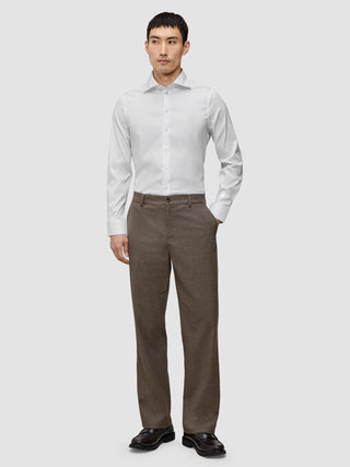 A man wearing an Elevated Shirt White Slim tucked into brown trousers and dark loafers.