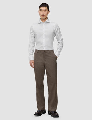 A man wearing an Elevated Shirt White Slim tucked into brown trousers and dark loafers.