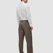 A man seen from behind wearing an Elevated Shirt White Slim tucked into brown trousers and dark loafers.
