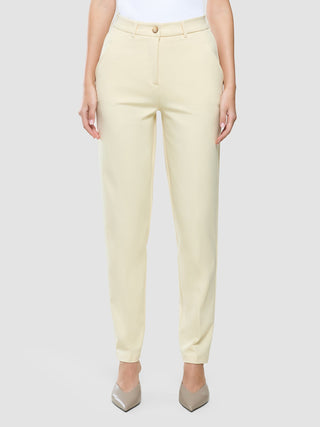 A person wearing Women Essential Pants Tapered Misty Yellow.