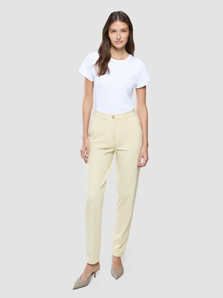 A woman wearing a white t-shirt and Women Essential Pants Tapered Misty Yellow.