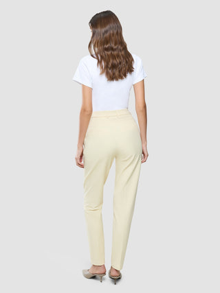 A woman viewed from behind wearing a white t-shirt and Women Essential Pants Tapered Misty Yellow.