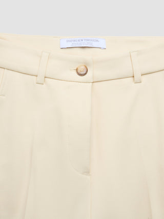 Close-up of cream-colored Women Essential Pants Tapered Misty Yellow with a button closure and a Shaping New Tomorrow brand label inside the waistband.