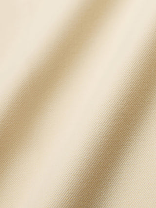Close-up of beige fabric on the Women Essential Pants Tapered Misty Yellow, featuring diagonal weave lines and soft folds that showcase the 360° stretch of these high-waisted pants.