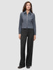 A model wearing an Essential Short Zip Jacket Dark Grey Melange with a minimalist collared zip-front and wide-leg black trousers.