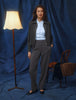 A woman wearing a dark grey melange Essential Short Zip Jacket over a light blue collared shirt and matching trousers.