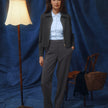A woman wearing a dark grey melange Essential Short Zip Jacket over a light blue collared shirt and matching trousers.