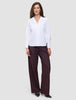 A woman wearing a white Madison Shirt with a notched collar and dark pinstriped wide-leg trousers.