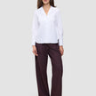 A woman wearing a white Madison Shirt with a notched collar and dark pinstriped wide-leg trousers.