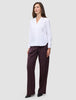 A woman wears the white Madison Shirt featuring a notched collar, paired with loose-fitting dark pinstriped trousers.