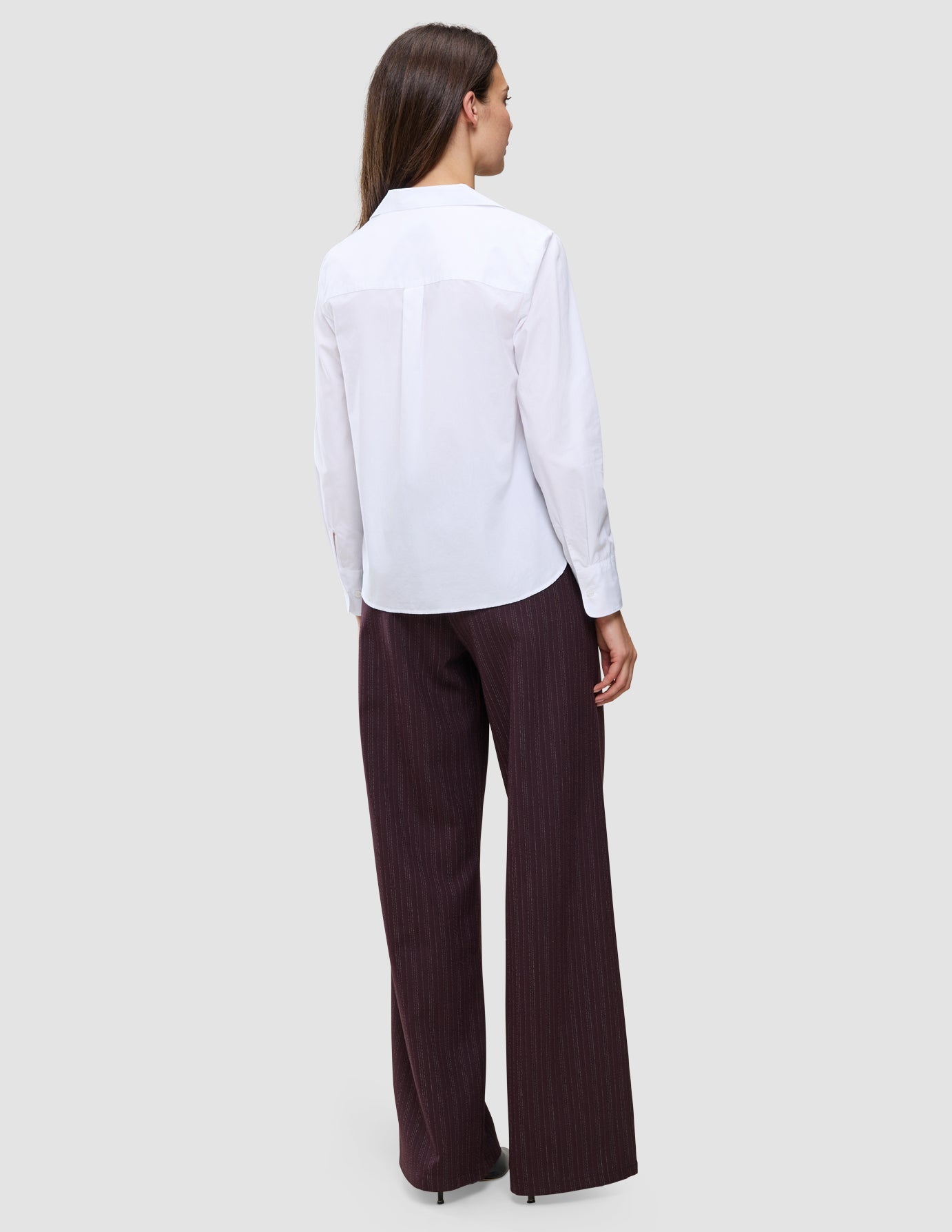 A woman seen from behind wearing a white 100% cotton Madison Shirt White and dark pinstriped wide-leg trousers.