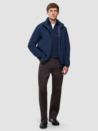 A man wearing a navy blue zip-up jacket over a sweater, paired with Marco Jeans Dark Brown and black shoes.