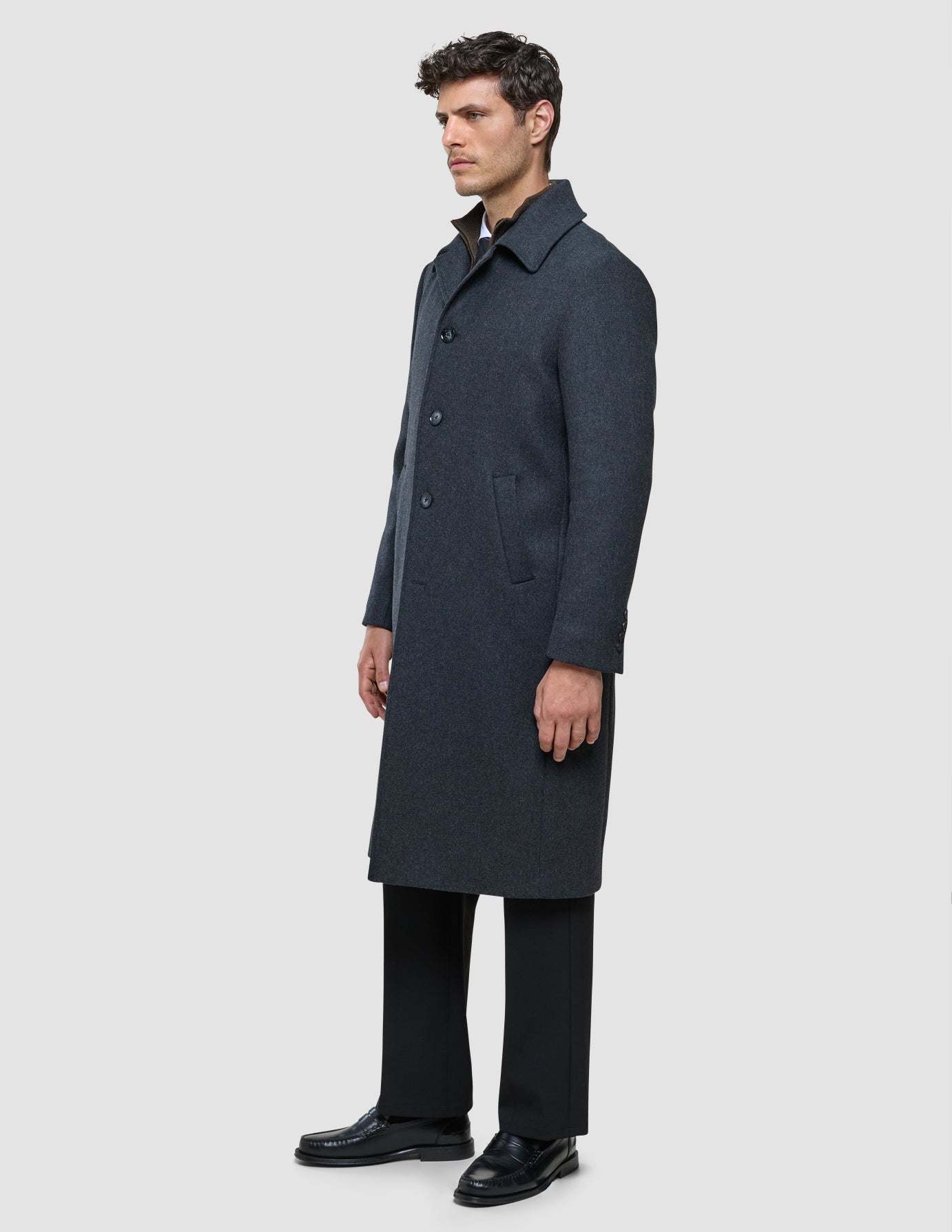 A man wearing a Maxi Wool Coat Dark Grey over a shirt and dark trousers.