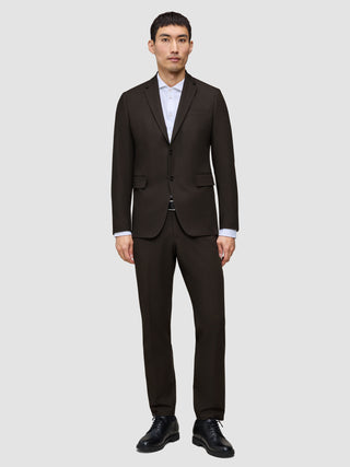 A man wears a Motion Blazer Regular Cognac over a white collared shirt and black dress shoes, reflecting a clean Scandinavian design.