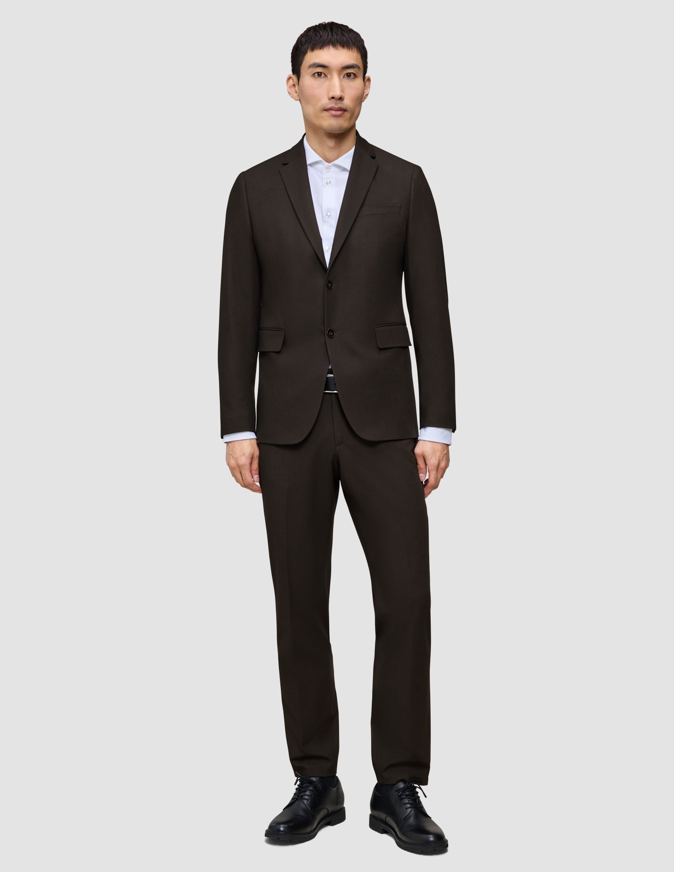 A man wears a Motion Blazer Regular Cognac over a white collared shirt and black dress shoes, reflecting a clean Scandinavian design.