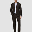 A man wearing a Motion Blazer Regular Cognac tailored blazer, paired with a white button-down shirt, black belt, and black dress shoes.