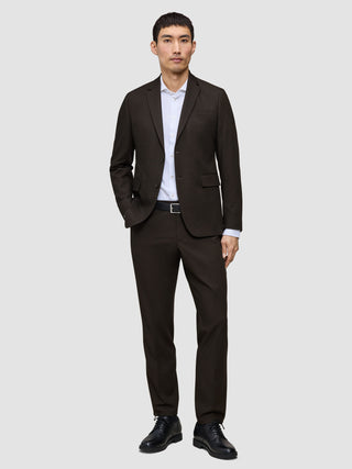 A man wearing a Motion Blazer Regular Cognac tailored blazer, paired with a white button-down shirt, black belt, and black dress shoes.