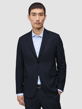 A man wearing a Motion Blazer Regular Midnight Blue in a dark blue, 360° stretch fabric over a light blue pinstriped button-down shirt.