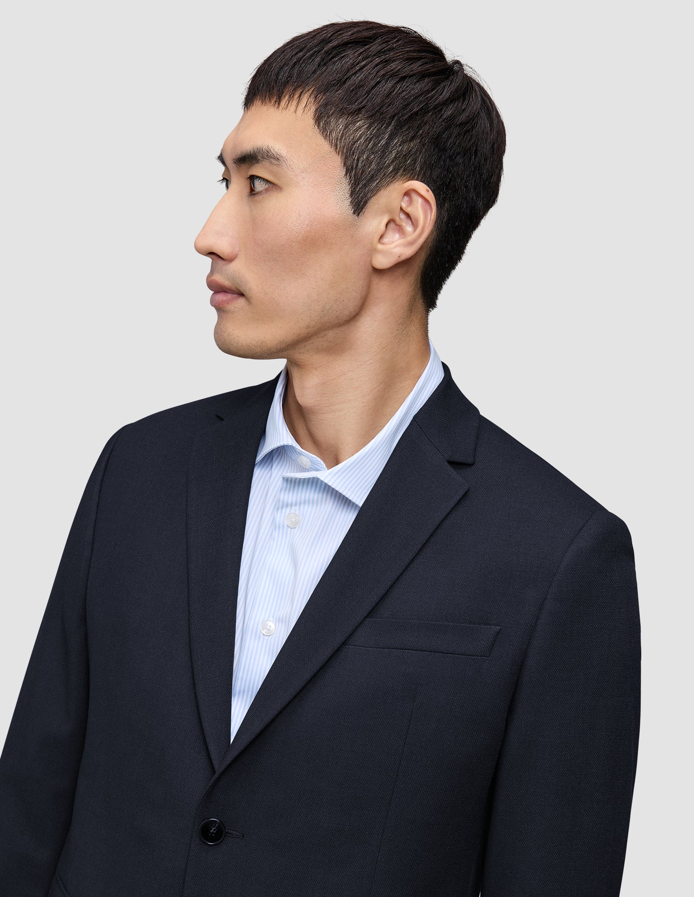 A person in profile wearing a tailored Motion Blazer Regular Midnight Blue over a light blue pinstriped dress shirt.