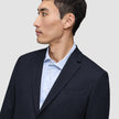 A person in profile wearing a tailored Motion Blazer Regular Midnight Blue over a light blue pinstriped dress shirt.
