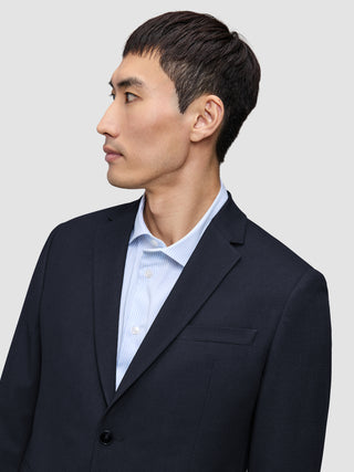 A person in profile wearing a tailored Motion Blazer Regular Midnight Blue over a light blue pinstriped dress shirt.