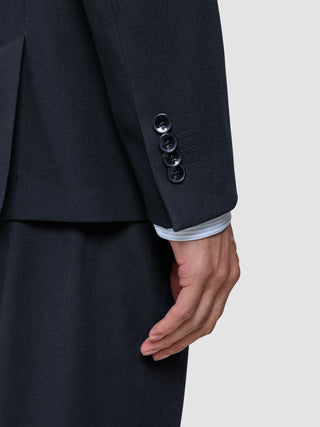 A dark blue sleeve of the Motion Blazer Regular Midnight Blue with four buttons at the cuff and a glimpse of a light-colored striped shirt sleeve underneath.