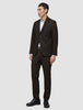 A man wearing a Motion Blazer Slim Cognac and matching trousers in lightweight breathable fabric, paired with a white button-down shirt and black dress shoes.