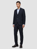 A man wears a Motion Blazer Slim Midnight Blue jacket and matching trousers, paired with a light blue button-down shirt and dark leather loafers.