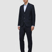 A man wears a Motion Blazer Slim Midnight Blue jacket and matching trousers, paired with a light blue button-down shirt and dark leather loafers.