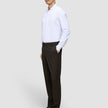 A man stands with his hand in his pocket wearing a white dress shirt and Motion Suit Pants Regular Cognac, which feature 360° stretch.