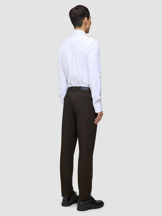 A person viewed from behind, wearing a white button-down shirt and Motion Suit Pants Regular Cognac with black dress shoes.