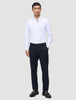 A man wearing a white button-down shirt, Motion Suit Pants Regular Midnight Blue, and dark leather loafers.