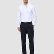 A man wearing a white button-down shirt, Motion Suit Pants Regular Midnight Blue, and dark leather loafers.
