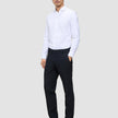 A man in a white button-down shirt and Motion Suit Pants Regular Midnight Blue stands with his hand in his pocket.