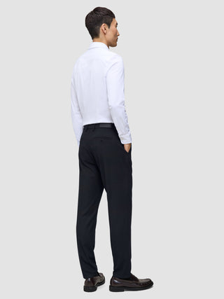 A man viewed from behind, wearing a white button-down shirt and Motion Suit Pants Regular Midnight Blue with his hands in his pockets.