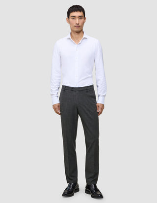 A man wearing a white button-down shirt, Motion Suit Pants Regular Pepper Grey, and black dress shoes.