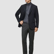 A man wearing a black blazer, grey turtleneck, and Motion Suit Pants Regular Pepper Grey.