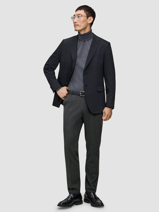 A man wearing a black blazer, grey turtleneck, and Motion Suit Pants Regular Pepper Grey.