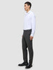 A person seen from the side wearing a white button-down shirt, Motion Suit Pants Regular Pepper Grey, and black loafers.