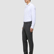 A person seen from the side wearing a white button-down shirt, Motion Suit Pants Regular Pepper Grey, and black loafers.