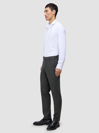 A person seen from the side wearing a white button-down shirt, Motion Suit Pants Regular Pepper Grey, and black loafers.